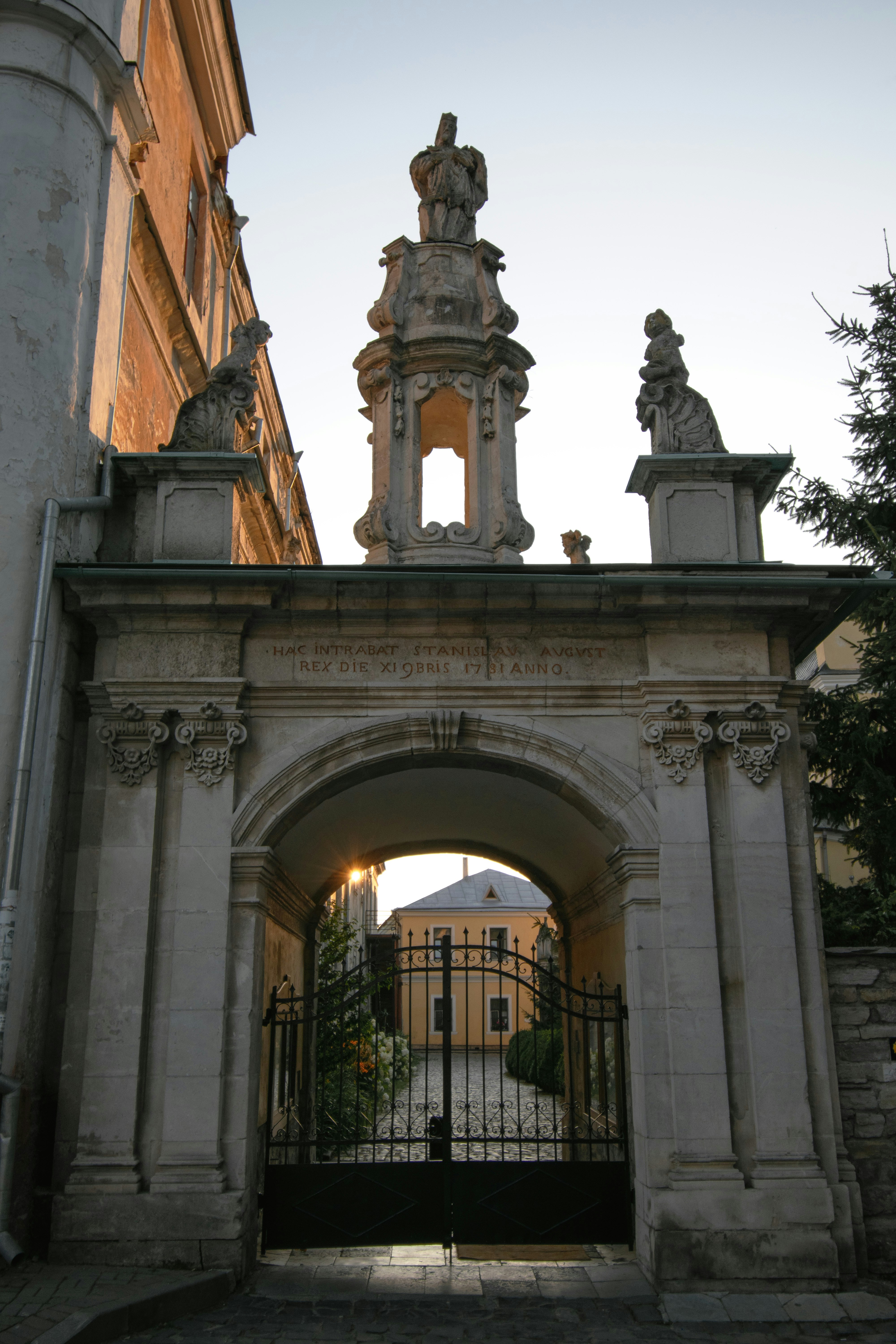 A stone archway leads to a gated entrance.